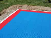 Close-up of a corner of blue and red backyard basketball court in Beverly, MA.