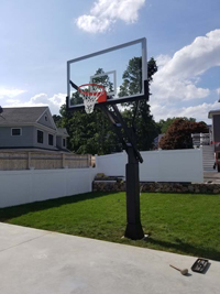 Hoop system ready to go by concrete base for backyard basketball in Boston.