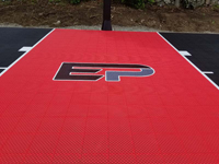 Closeup of red key area and custom logo on black and red basketball court in Brockton, MA.