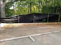 This shows the back of the form, unusually deep, and the metal reinforcement in place prior to poring the back half of the court base for the Chestnut Hill, MA transformation of a tight backyard space into a slate green basketball court with custom containment net fencing atop wooden fence.
