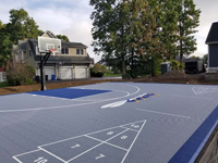 Looking from front left corner toward back left corner of backyard basketball court in Cumberland, RI. Optional shuffleboard is visible, along with custom bug logo.