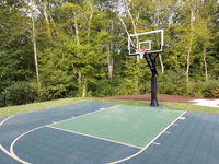 Angled view from right of front center toward key and hoop of basketball court in shades of green in Dartmouth, MA.