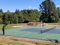 Side view of large olive and slate green basketball and tennis court in Easton, MA, showing off the four hoops.