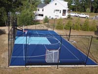 Lenthwise view of pretty blue backyard court in Groveland MA, featuring pickleball, basketball, and off-label plans for hockey by the resident youngsters.
