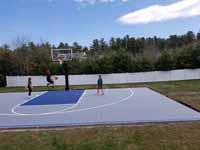 People playing on newly installed Titanium and navy blue residential basketball court in Hanson, MA. Recently poured base shown here, waiting for cement to dry and cure.