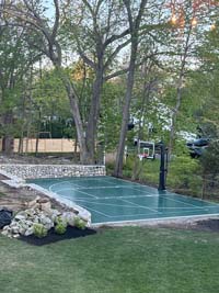 Green basketball and pickleball court nestled in a beautiful residential landscape in Hingham, MA.
