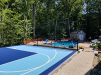 View of part of right side of small residential basketball court with pool in background in Medway, MA.