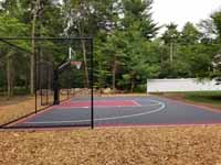 Backyard basketball court with graphite and red Versacourt surface in Middleborough, MA.