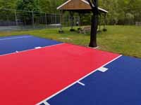 Resurfaced asphalt basketball court in blue and red at Seekonk Swimming and Tennis Club in Seekonk, MA.