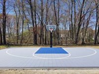 Ice and royal blue tile on concrete basketball court in South Hadley, MA, looking straight back toward hoop.
