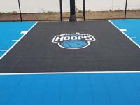 Closeup of custom Hines Hoops logo in black key on royal blue basketball court in South Yarmouth, MA.