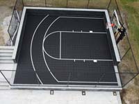 Close overhead view of small basic black basketball court in Weston, MA.