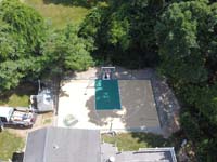 Context view from well overhead of small sand and green basketball court with custom logos and writing in Westwood, MA.
