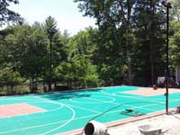 Backyard basketball court in Pembroke, MA, green and red with volleyball and lighting options.