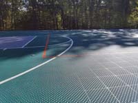 Surface between end and center court areas of large emerald green and titanium backyard basketball court in Bolton, MA.