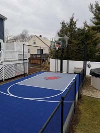 Small blue and grey backyard basketball court with custom H logo in Braintree, MA.
