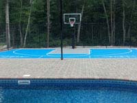 Basketball and shuffleboard game court in light blue and titanium tiles on concrete foundation integrated with a pool and deck in Wareham, MA.