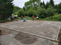 After excavation and removal of all organic material, it's packed gravel to go under the concrete base for a backyard court in Easton, MA.