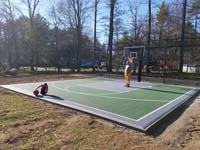 Backyard basketball court with lighting for night play and a batting cage in Hanover, MA.