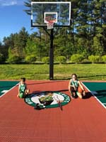 Kids in Celtics uniforms on backyard basketball court with Versacourt custom logo in Londonderry, NH.