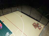 Right side of sand and green Londonderry court, with overhead lights on, highlighting custom BC Eagles logo.