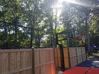 A close look at the hoop and specially created wood and mesh fencing for graphite and orange residential basketball court in Walpole, MA.