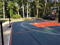 Graphite and orange backyard basketball court where there was previously a pool in Walpole, MA.
