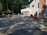 Pouring reinforced concrete base for graphite and orange backyard basketball court replacing a dead pool in Walpole, MA.