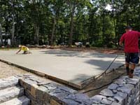 Grooming cement base for graphite and orange residential basketball court replacing a dead pool in Walpole, MA.