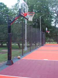 Surfaced giant multiple basketball court at Frost Valley YMCA in Claryville, NY. Features orange, black and burgundy tiles, plus custom logos.