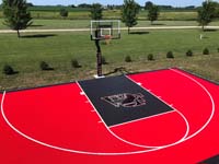 Example of a backyard basketball court in bright red with a black key and custom logo.
