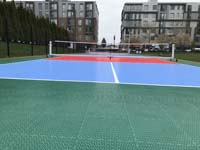 View down pickleball court close to tile surface, looking toward D Street and apartments, at Lawn on the D in Boston, MA.
