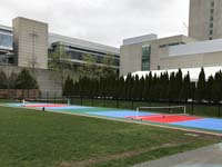 Angled side view of the whole double pickleball court with portable nets at Lawn on the D in Boston, with both the convention center and Westin Hotel visible in background.