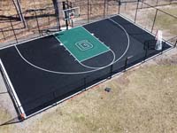 Lower overhead view of black and green home basketball court with custom G logo in Canton, MA.