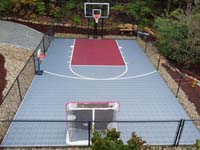 Silver and burgundy custom backyard basketball court in Chelmsfor, MA, with separate hockey net and toddler hoop purchased separately.
