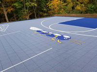 View of center surface of Cumberland, RI basketball court, looking toward left rear, with custom bug logo focal point in center.