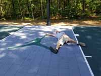 Slate green and titanium backyard basketball court with Michael Jordan custom logo in Duxbury, MA, showing homeowner having fun posing with celebrity likeness.