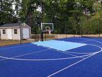 View of blue Groveland, MA basketball and pickleball court from front left toward hoop.