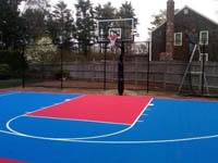 Bright blue and red backyard basketball court nearing completion in Halifax, MA.