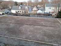 Hingham, MA court location after the landscape contractor has created a level surface on the front yard hillside, with form and reinforcement ready for cement for court base.