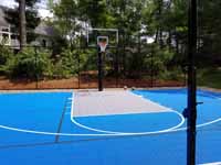 Residential backyard basketball court on asphalt in Massachusetts, in colorful blue and silver.
