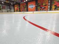 We traveled to Kapolei, Hawaii and inside to resurface two inline skate hockey rinks with Versacourt Speed Indoor tile. This is a finished view showing part of the faceoff circle and the adjacent skating surface.