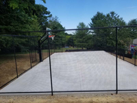 All the leveling and preparation is done, concrete base is in, and fence is up for monochrome blue hilltop home basketball court in Milton, MA.