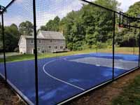 Backyard basketball court in village of Oakdale, Connecticut, in the historic town of Montville. Blue and silver surface with a custom logo that says Center Court with an orange basketball in place of the letter o.