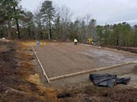 Hillside court primarily for pickleball, accessorized with a basketball goal and fencing, in Plymouth, MA. This shows the nearly completed form and rebar reinforcement for cement to be poured for the court foundation.