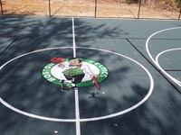 Relative close-up of custom Celtics logo in genter of basketball court in Raynham, MA.