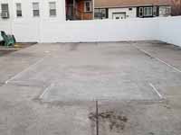 Outline of filled in pool is visible in existing concrete to be installed with a royal blue and ice blue basketball court, goal system, and containment fence in Revere Beach, MA.