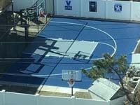 Royal blue and ice blue basketball court in Revere, MA. This was installed on existing concrete that included a cap on a filled in pool. Viewed from a tall adjacent building for an almost overhead shot ny the court owner.