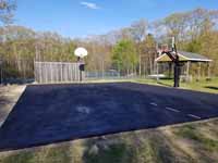 Asphalt basketball court at end of prep for resurfacing at Seekonk Swimming and Tennis Club in Seekonk, MA. This shows the trimmed, filled and leveled surface after sealcoating has been applied to repel water and extend life.