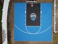Direct overhead drone view of stunning royal blue and black backyard basketball court, featuring a custom logo designed by the homeowner, located on Cape Cod in South Yarmouth, MA.